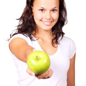 smiling young woman offering an apple