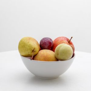 simple white bowl of fruit on white background