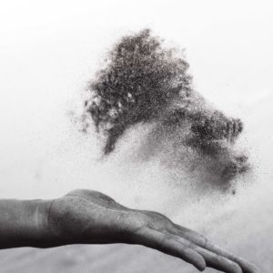 Black and white photo of hand tossing a cloud of dust