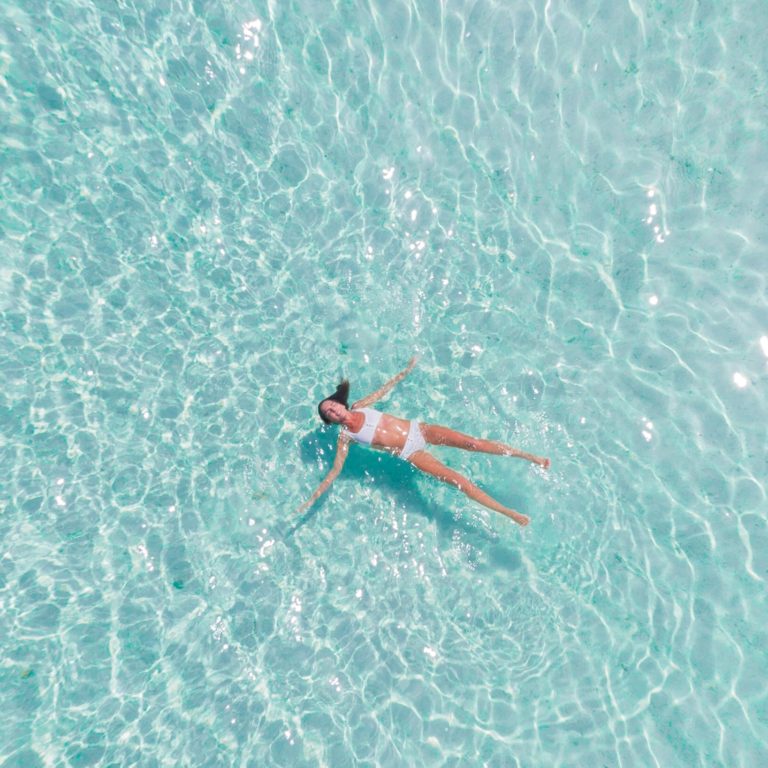 A calming photo of a woman floa turquoise sea